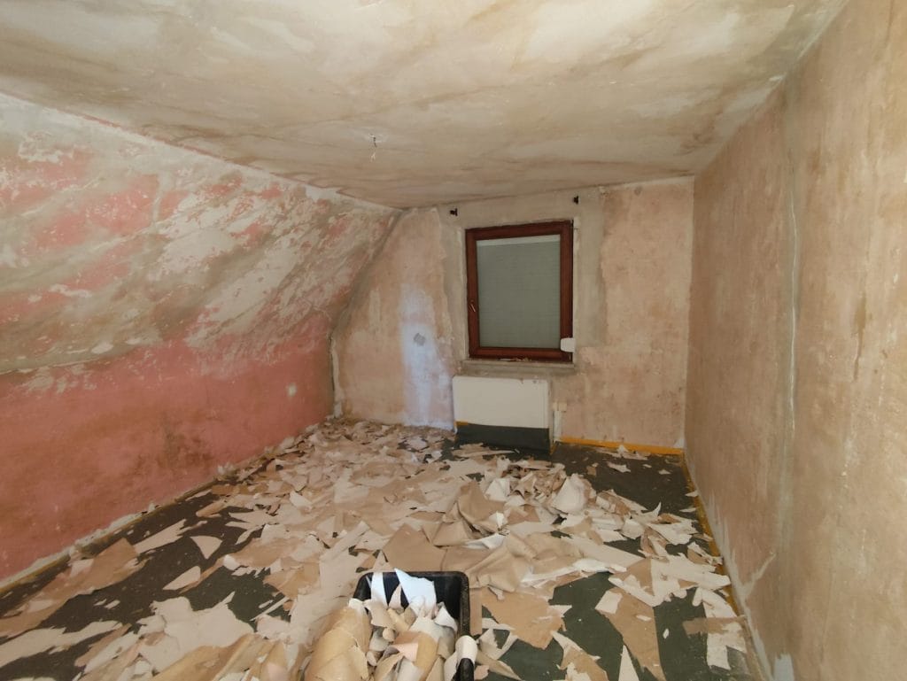 Wand mit entfernten Tapeten, sichtbaren Löchern und Rissen – Vorbereitung für Malerarbeiten und Renovierung