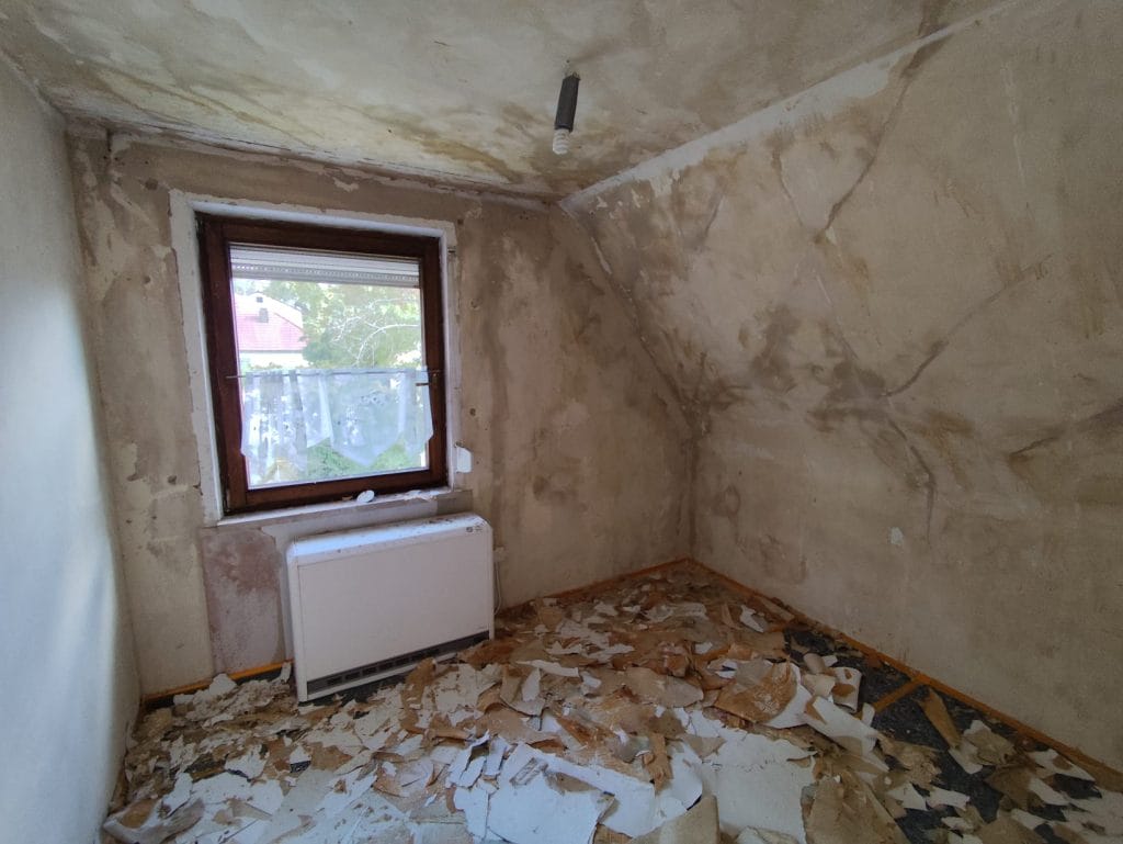 Raum mit entfernten Tapeten und beschädigten Wänden – Vorbereitung für Renovierung und Malerarbeiten
