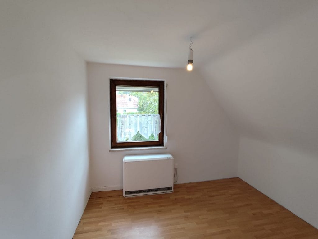 Renovierter Raum mit frisch gestrichenen Wänden und neuem Bodenbelag – saubere Malerarbeiten und Bodenrenovierung.